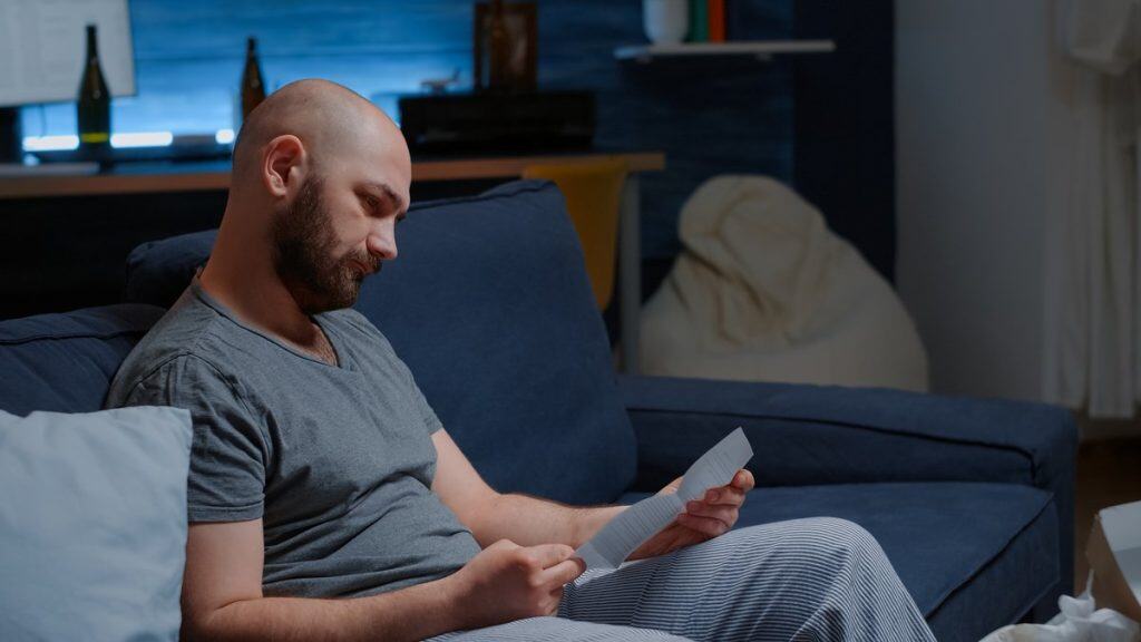 A man sitting on a couch reading a document