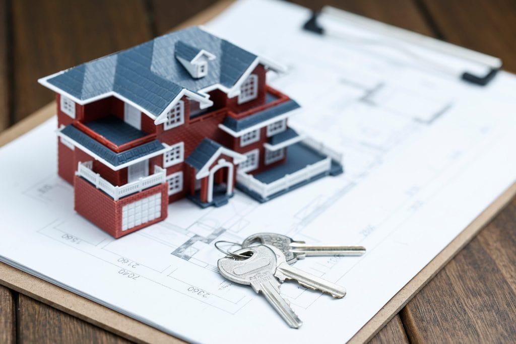 A model house with keys on architectural blueprints