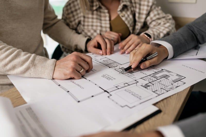 People reviewing architectural floor plans at a table
