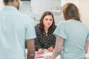A woman meeting with a couple across a table during an interview