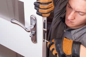 A man in work gloves installing a door lock