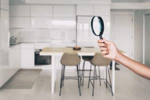 A hand holding a magnifying glass in a modern kitchen