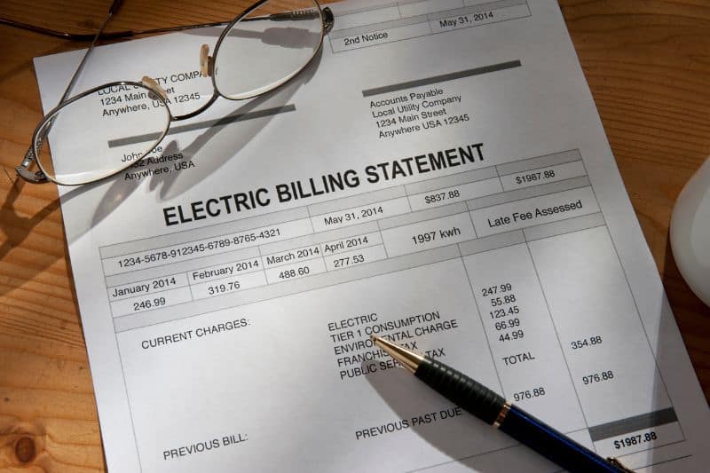 An electric billing statement with glasses and a pen
