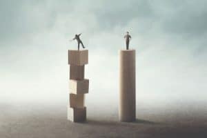 Two figures standing on stacked wooden blocks of different heights