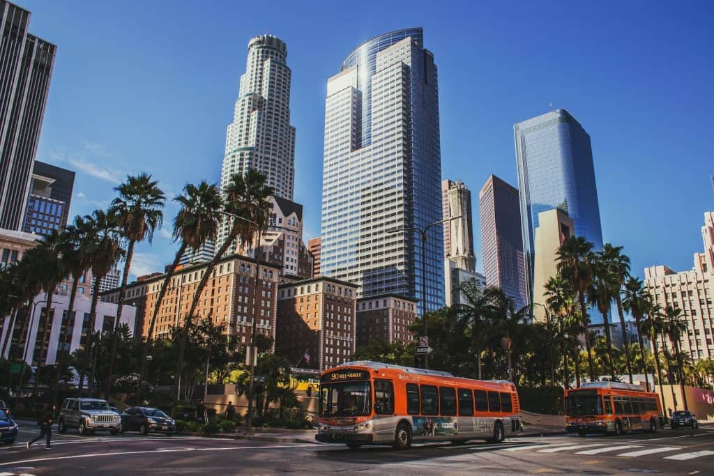 The downtown Los Angeles skyline with skyscrapers, palm trees, and a bus