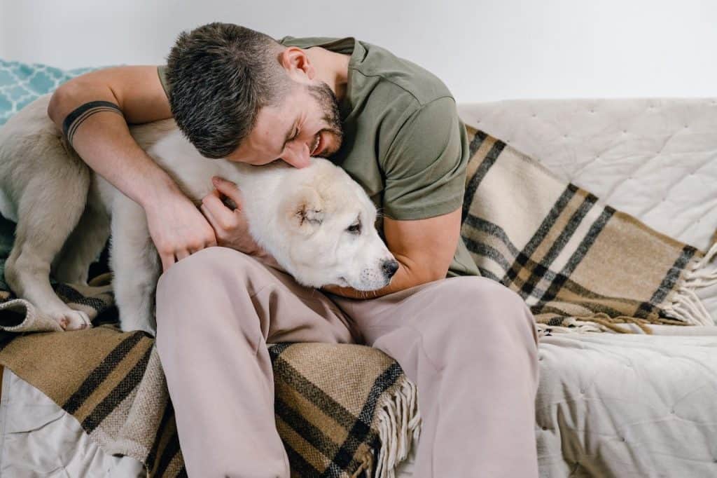 A man cuddling a dog on a couch
