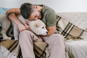 A man cuddling a dog on a couch