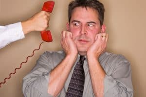A stressed man ignoring a red telephone receiver held out to him