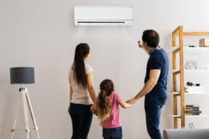 A family looking at a wall-mounted air conditioner in a living room