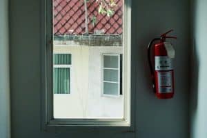 A red fire extinguisher mounted on an apartment building wall