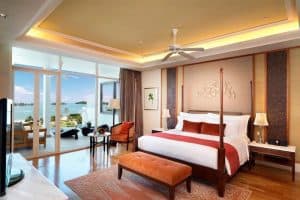 A luxury hotel suite with a four-poster bed and an ocean view