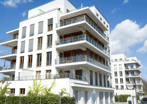 A modern white multi-story apartment building against a blue sky