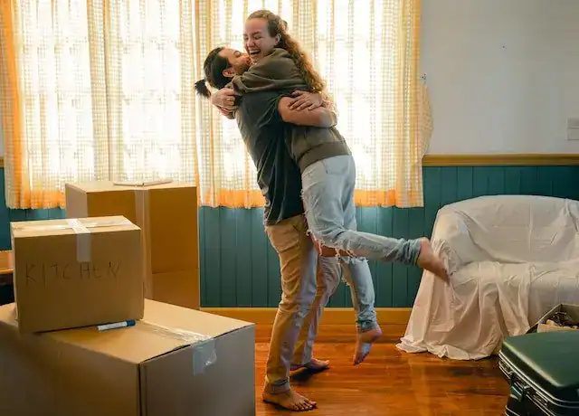 Smiling couple embracing among cardboard moving boxes in a new home